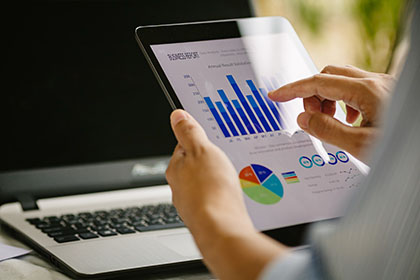 Businessperson reviewing tablet screen with business growth data charts.